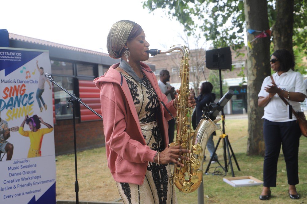 Saxophonist Oprah Atunrase performing live uplifting melodies beside the Connect Talent Music and Dance Club banner as attendees clap along